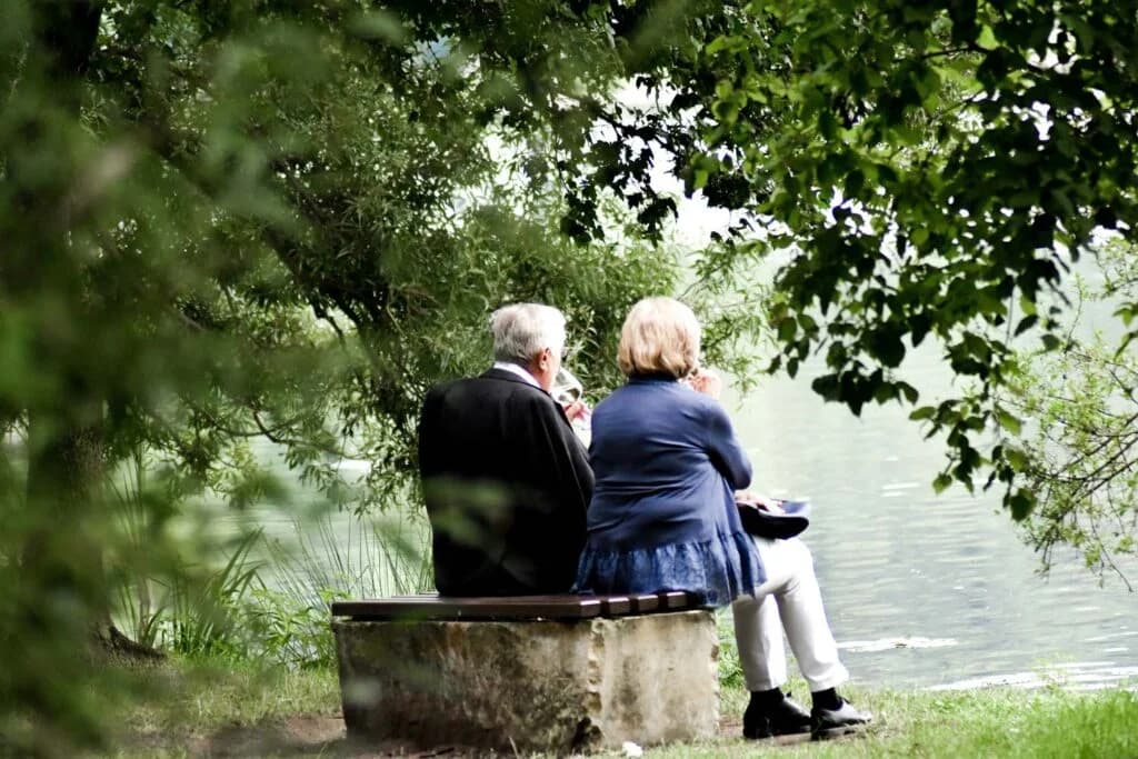 An older couple sitting together by a lake